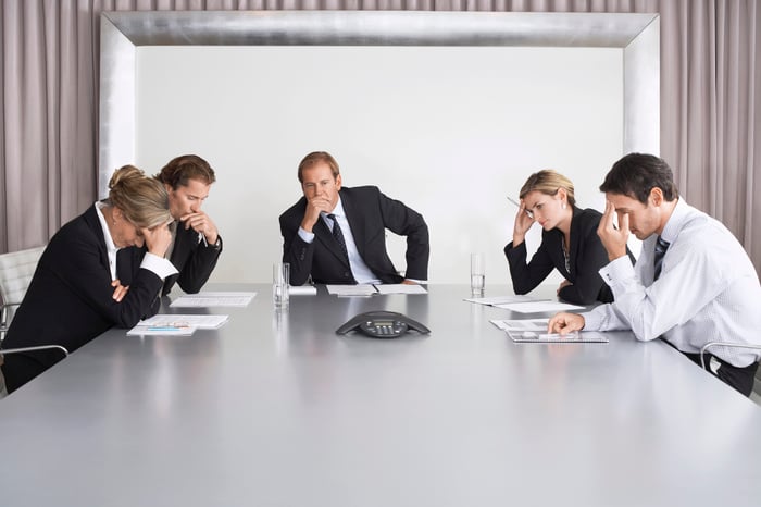 Management team around conference table looking worried