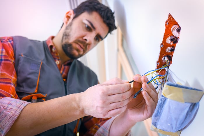 man connects wires coming from a wall