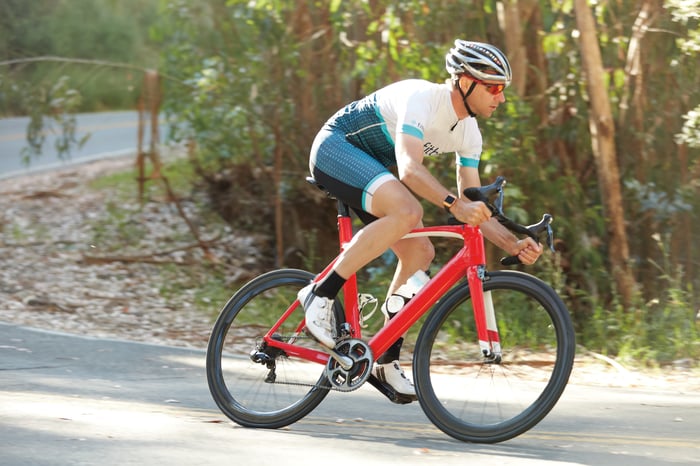 Biker dressed in Fitbit biking uniform riding downhill with Fitbit Ionic on his wrist.