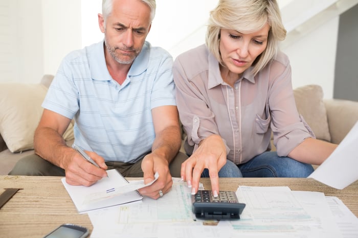 Mature couple looking at financial papers and using a calculator.