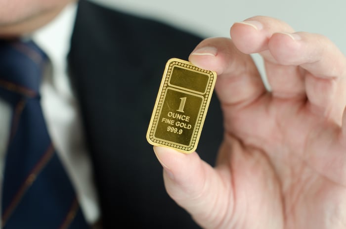 A man in a suit holding a gold ingot