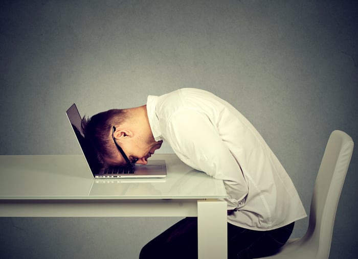 Man resting his head against a laptop