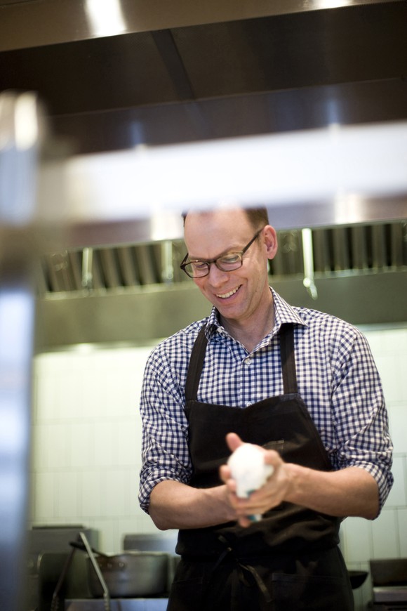 Steve Ells stands in a restaurant kitchen holding an object in his hands