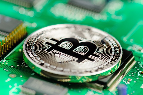 A bitcoin sitting on top of a computer board.