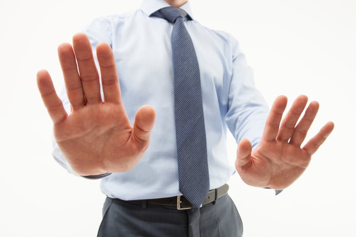 Businessman signaling rejection with raised palms.