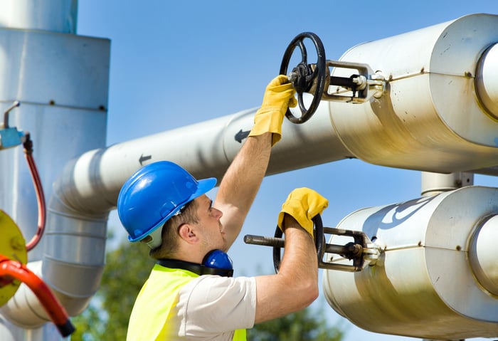 A man turning handles on a pipeline