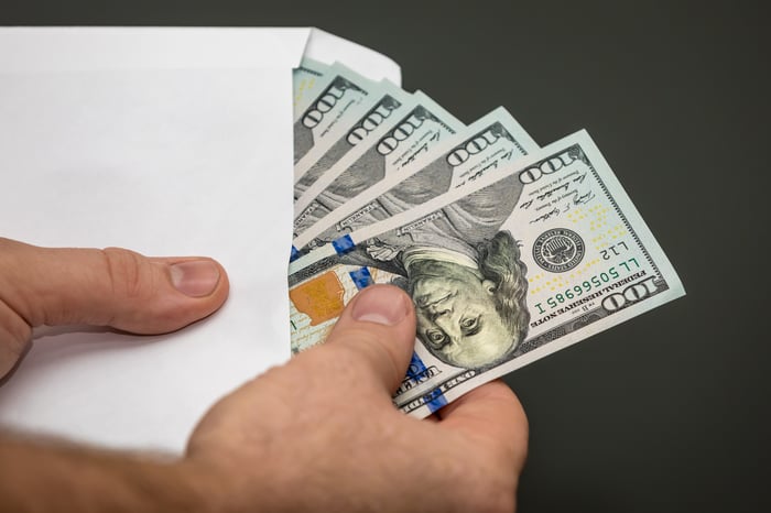 Man holding an open envelope with $100 bills