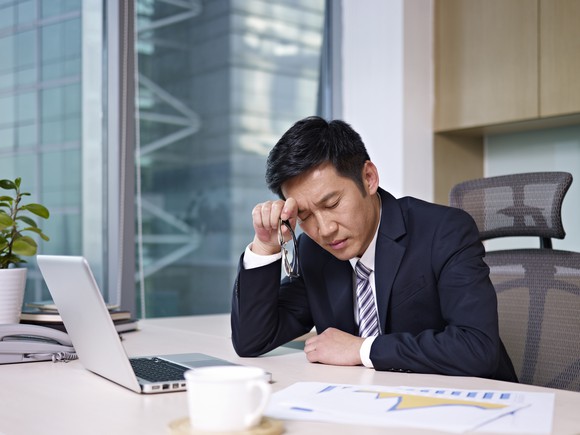A businessman in front of a computer thinking hard