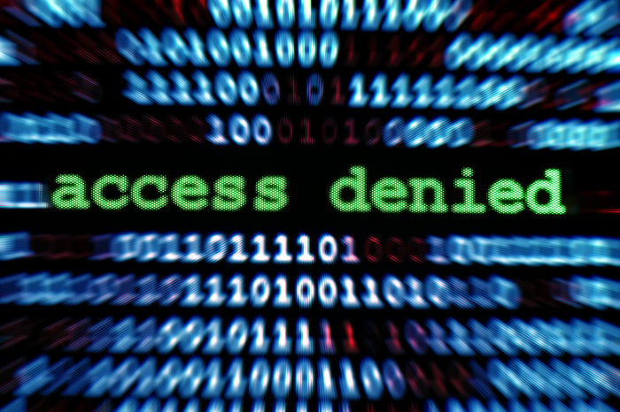 The words access denied on a computer screen, surrounded by binary code. 