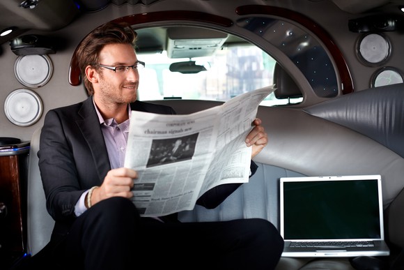 Man reading a newspaper in a limo