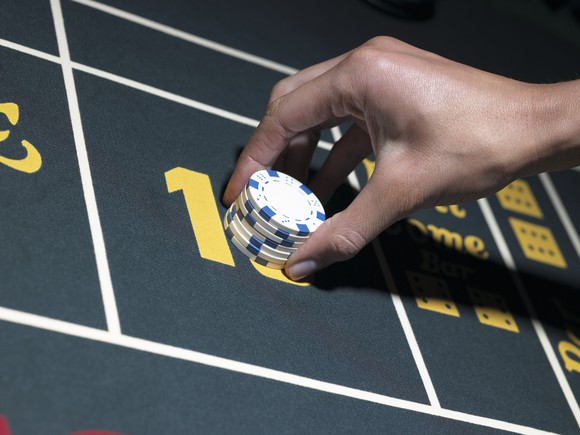 Hand placing gambling chips on a casino table.