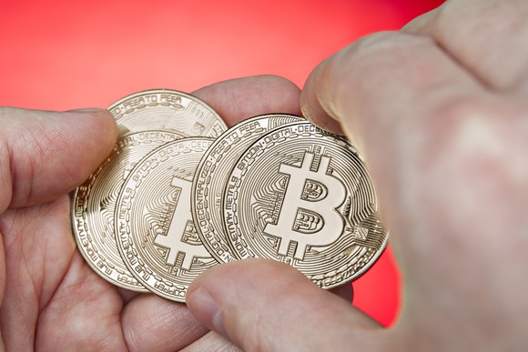 five golden bitcoins in someone's palm