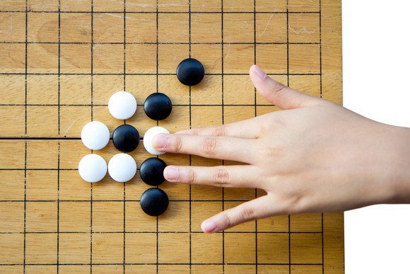 A hand placing a white stone on a Go board