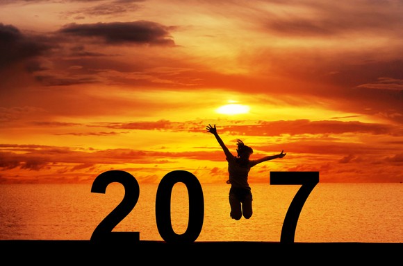 Woman jumping in front of the sea at sunset, celebrating 2017.