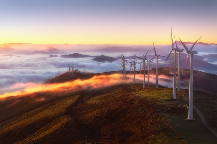 Wind turbines on the top of a mountain with fog below.