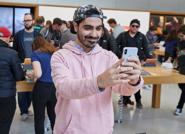 A man holding an iPhone X while looking at it.