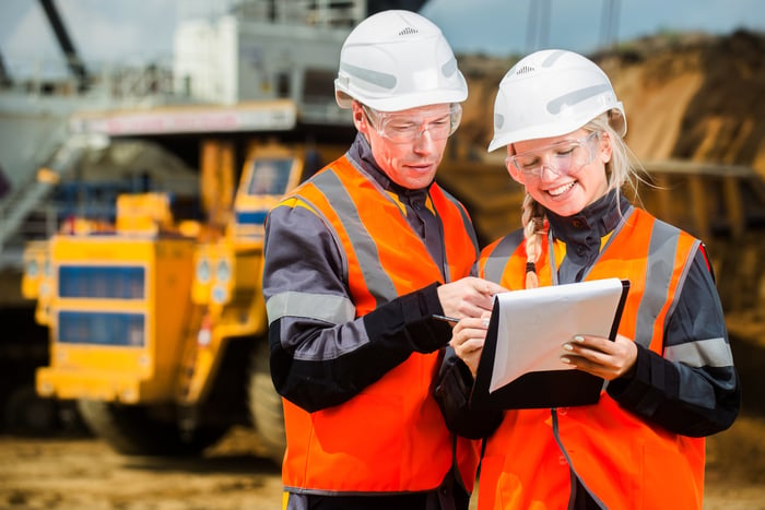 A man and a woman standing in front of mining equipment