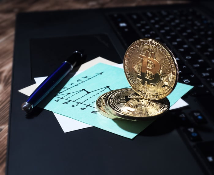 A physical Bitcoin Cash token atop a post-it note with a chart drawn on it.