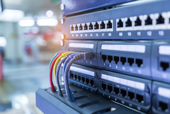 A rack of enterprise-class Ethernet switches with a few colorful cables plugged in.