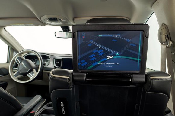 A rear-facing display screen in a self-driving car shows a map route.
