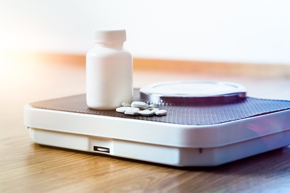 Pills and pill bottle on top of a scale