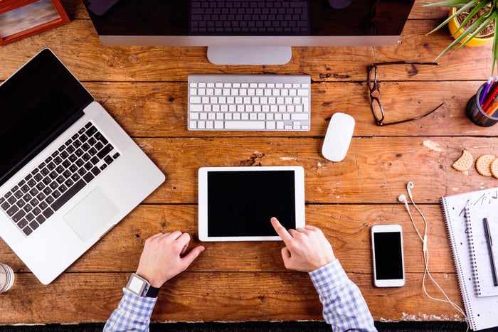 Man with tablet, smartphone, laptop, and computer.