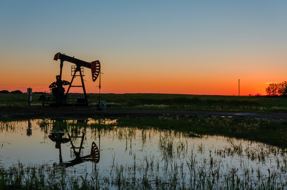 An oil pump next to a pond.