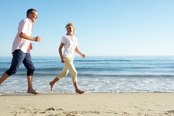 Mid-aged couple running along the beach