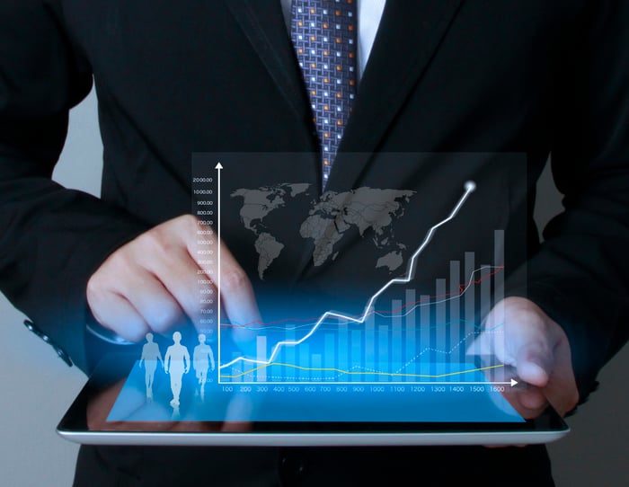 A man in a suit touching tablet screen with a chart coming off of it