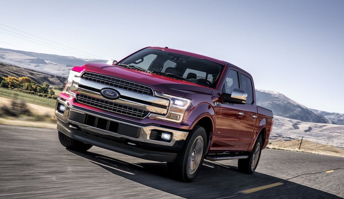 A red 2018 F-150 pickup on a rural road.