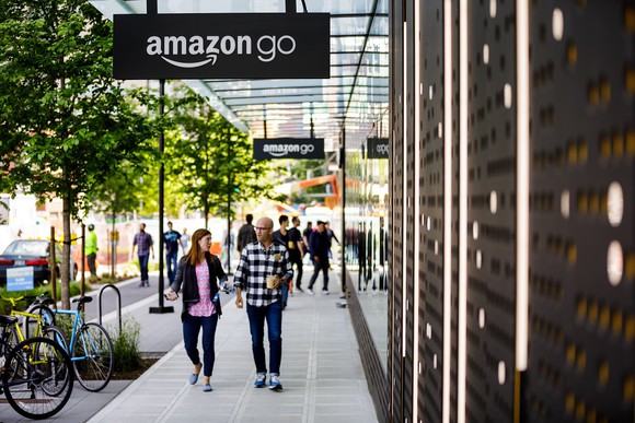 A man and a woman walk under the Amazon Go store signs in Seattle.