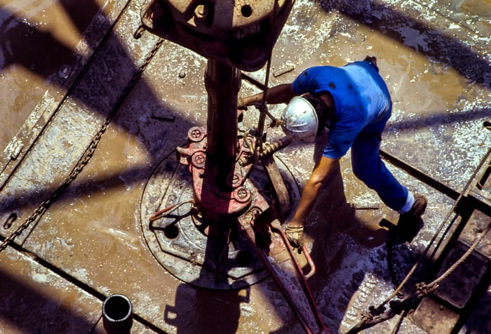 Oil rig worker in a blue shirt working at a drill site