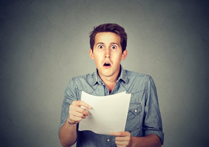 Man looking at a document with a shocked expression on his face