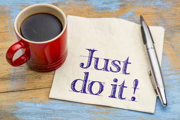 red mug of black coffee next to pen and napkin on which is written just do it!