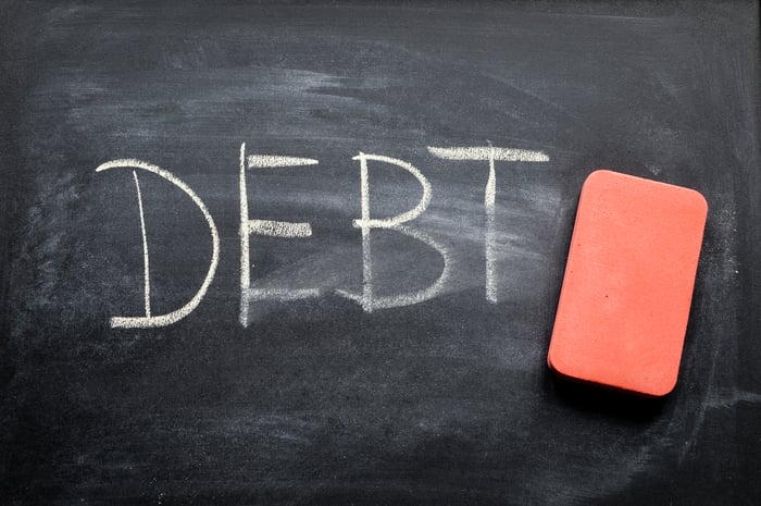 The word debt written on a chalkboard with an eraser next to it.