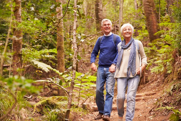A senior man and woman holding hands while hiking