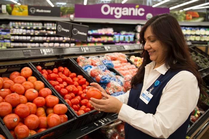 A Walmart employee examining a tomato.