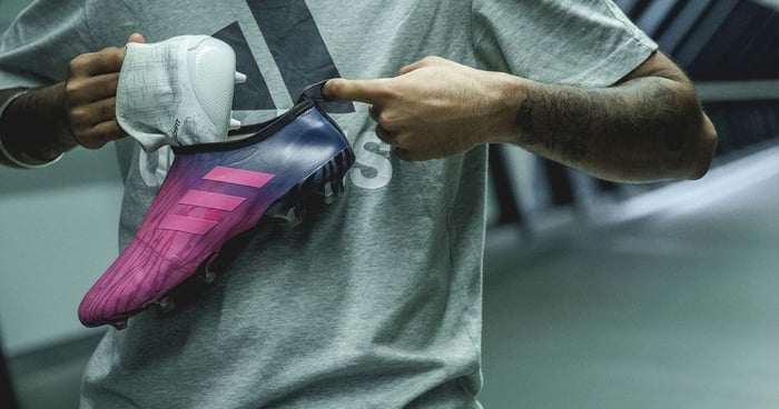 An employee putting together a pair of Adidas shoes.