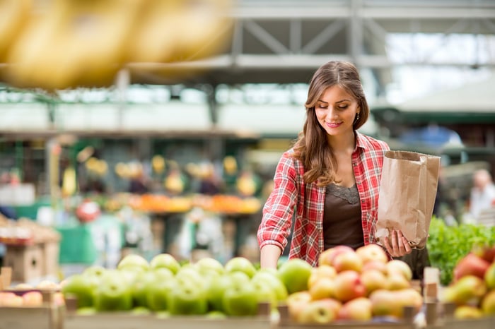 A person shopping in the produce department of a grocery store.