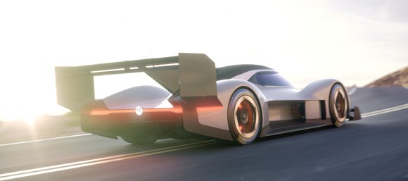 The VW I.D. R Pikes Peak, a low-slung grey racecar with a big rear wing, is shown on a mountain road.
