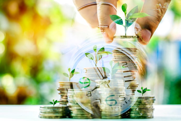 Sprouts growing out of stacks of coins overlaid with clock.