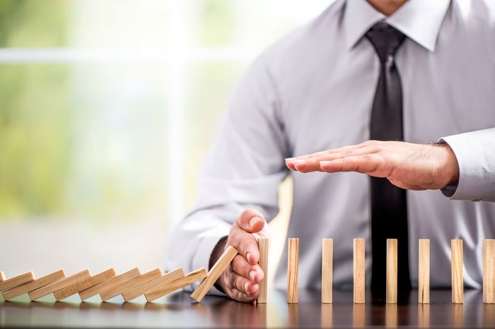 Man holding hand to prevent dominoes from falling.