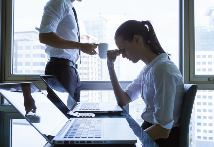 Woman holding her head at a conference room table