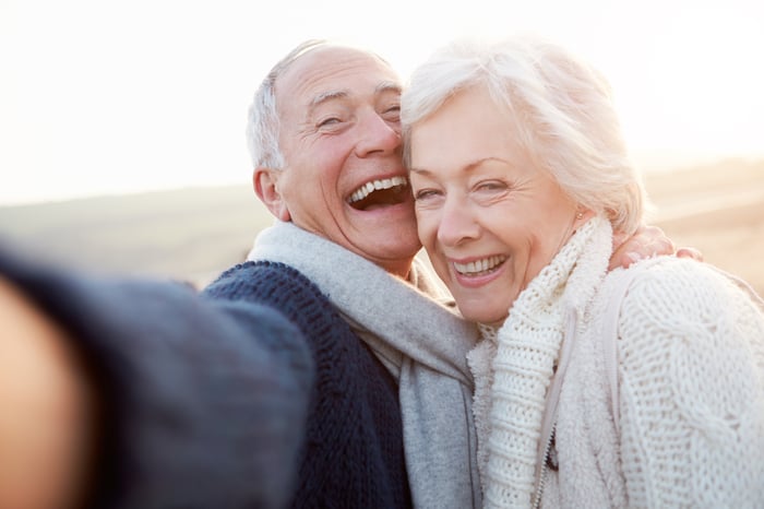 Senior couple laughing while taking a selfie at the beach