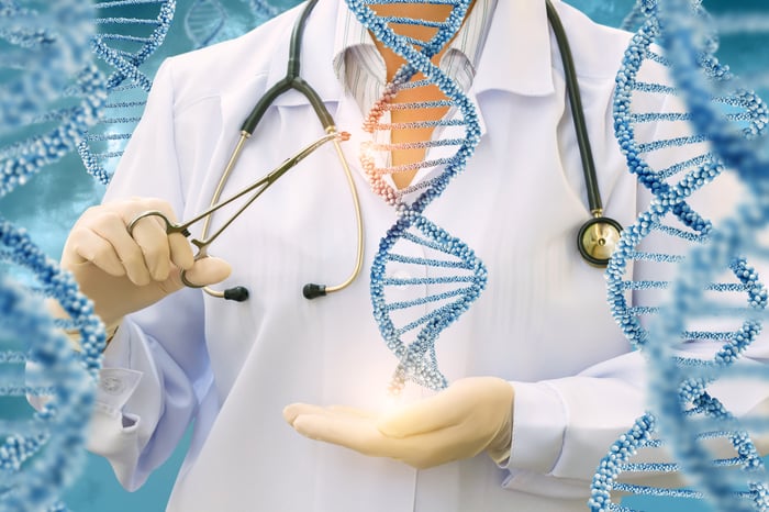 A researcher in a lab coat holding a double helix in one hand while snipping a piece of DNA from it using scissors in her other hand.