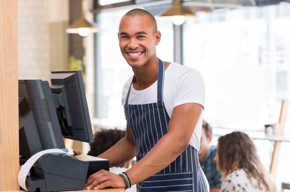 A smiling millennial waiter in a restaurant.