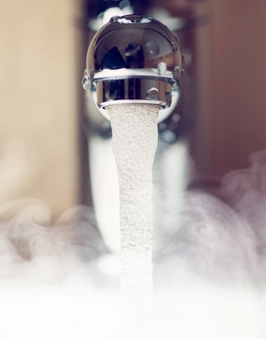 Hot water coming out of a faucet and generating steam.