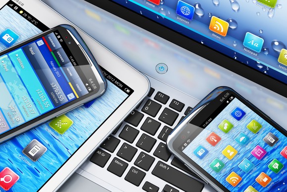 Digital devices like smartphones and tablets on a laptop.