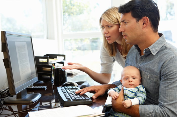 Worried parents holding a baby and reading an online article. 