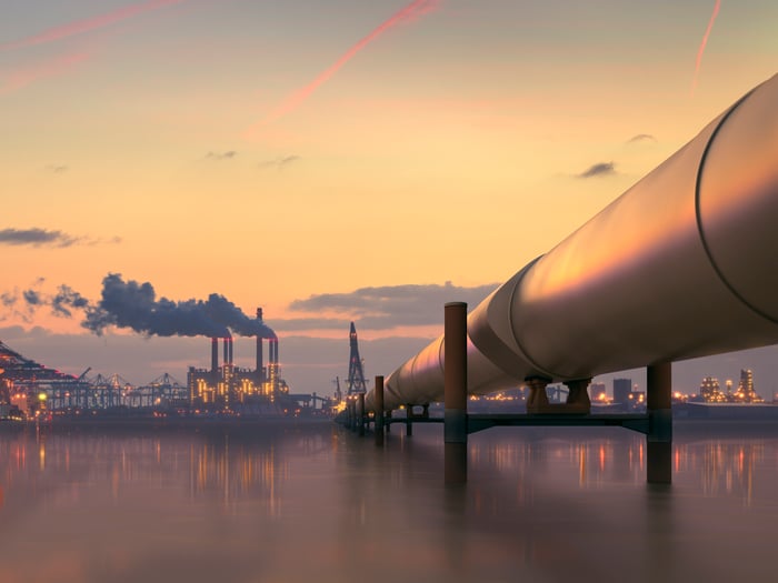 A pipeline heading into an industrial area at dusk.